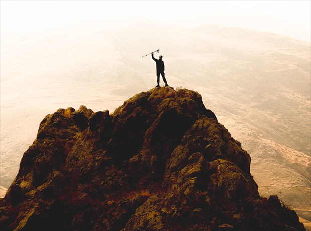 Person standing on a mountain summit with an arm raised